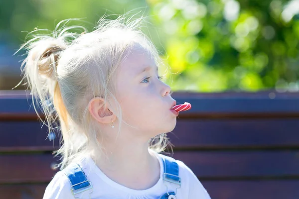 Uma criança com doces em suas mãos no fundo da fonte de verão . — Fotografia de Stock