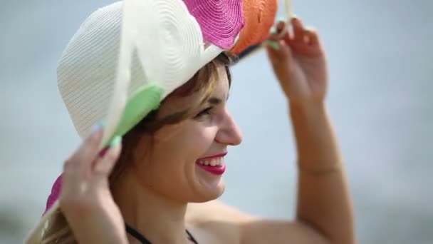 海の近くに広いフィールドを持つ帽子をかぶった女の子 大きな帽子をかぶった美しいブルネットの女の子が海を見る — ストック動画