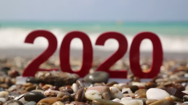 2020年の観光シーズン ピントがない数字2020は海のビーチにあり その後ろには見える海の波と太陽があります — ストック動画