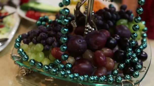 フルーツとビーズとガラスボウル結婚式のテーブルを飾るために花輪でビーズに包まれた新鮮なフルーツ — ストック動画