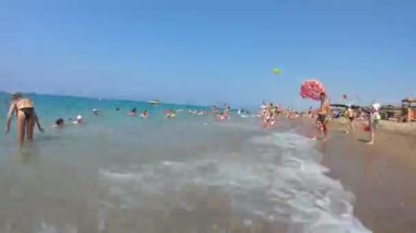 Manavgat, Türkiye 10 Temmuz 2019: Sahilde dinlenen insanların videosu Birinci şahıs videosu, denizde yüzen ve sahilde dinlenen turistlere bakan bir kişi videosu.