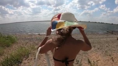 Nehre doğru yüzmek için koşan genç ve mutlu bir kadının arkasından manzara. Bir kız sahil boyunca suya koşar..