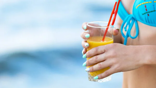 Un vaso con zumo de naranja en manos femeninas . — Foto de Stock