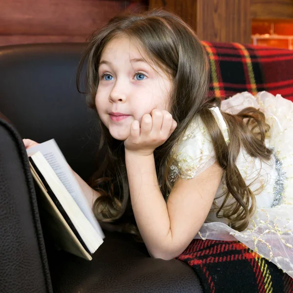 Dziecko czyta ciekawą książkę przez choinkę. — Zdjęcie stockowe