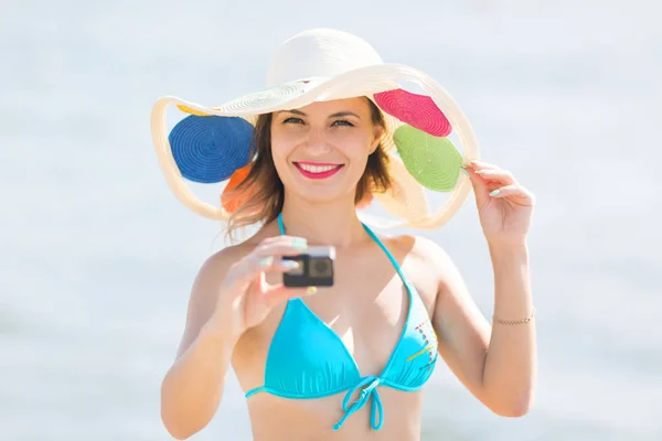 A girl shoots a video of the sea on a small camera