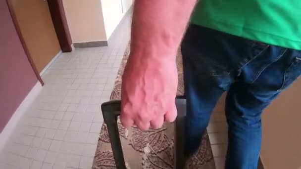 一只男性手沿着旅馆的走廊把一个手提箱拉着把手拉到房间 男性游客在旅馆里滚动一个手提箱 — 图库视频影像