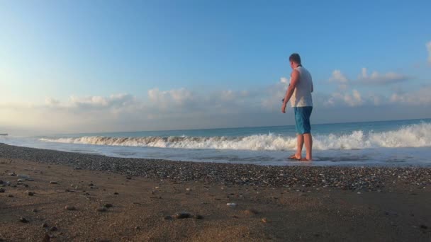 写真家は夜明けにビーチを歩きます 休暇中に写真カメラカメラマンを持つ男が海浜を散歩 — ストック動画