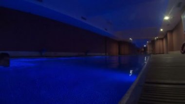 Bir adam evinde kendi havuzunda yüzer. Bir adam mavi koyu ışıkta özel bir havuzda yüzer..