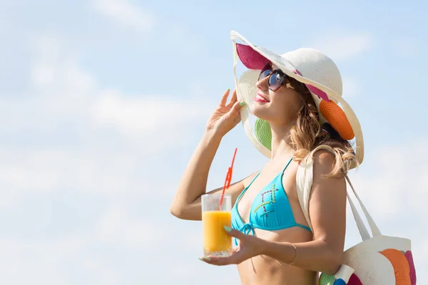 Una chica está junto al mar con un vaso de jugo . — Foto de Stock