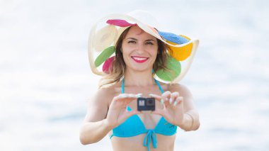 Plajda mini kameralı bir kız.,