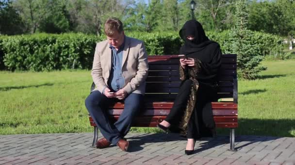 Unfamiliar Man Woman Sitting Bench Blond Man Islamic Woman Sitting — Stock Video