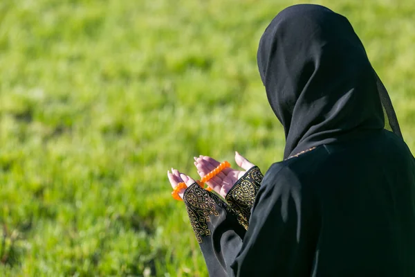 市内公園でのイスラム教徒の女性の祈り イスラム教徒の女性は公園の緑の草の上に座って朝の祈りを行う — ストック写真