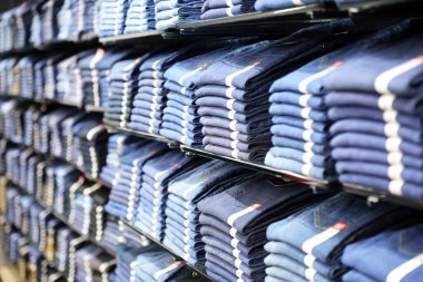 Mağazadaki bir rafta giysi çeşitleri. Mağaza tezgahında bir yığın erkek giysisi var..