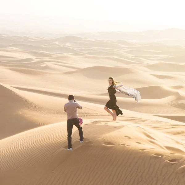 Exclusive photo shoot of a woman in the desert. Magazine advertising filming. The work of the photographer and model in the desert of Dubai.