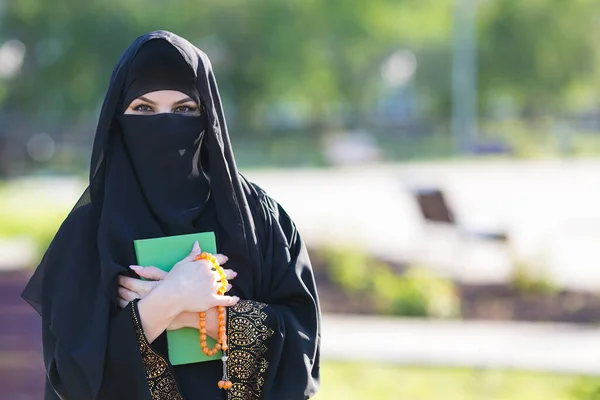 一个女人手里拿着卡兰的圣书 祈祷着 穆斯林妇女站在那里 手里拿着头巾 — 图库照片