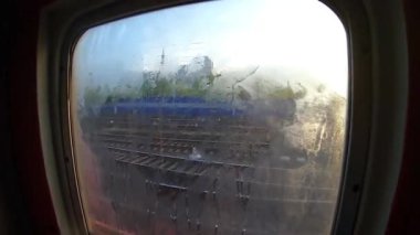 Tren vagonunun girişinde sisli bir pencere var. Pencerenin dışında şafak söküyor..