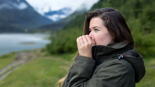 Soğuk bir sabahta bir kadın sıcak nefesle ellerini ısıtır. Dişi turist soğuk bir sabahta dağlarda onları ısıtırken ellerine üfledi.