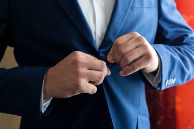 Bir adam ceketinin düğmesini karnına bağlar..