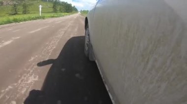 Bir arabanın kirli tarafı yolda gidiyor. Düşük bir açıdan yakın plan.