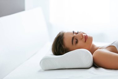 Ortopedik yastık. Beyaz yastık yatakta yatan kadın. Yüksek çözünürlük.