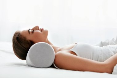 Neckroll yastık. Beyaz yatakta uyuyan yastık üzerinde istirahat kadın. Yüksek çözünürlük.