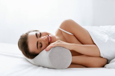 Neckroll yastık. Beyaz yatakta uyuyan yastık üzerinde istirahat kadın. Yüksek çözünürlük.