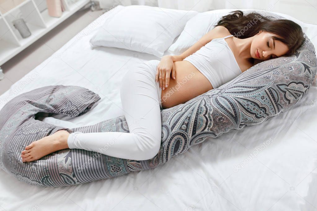 Body Pillow. Pregnant Woman Sleeping On Pregnancy Pillow On White Bed. High Resolution