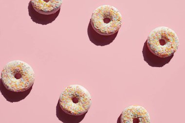 Pembe bir arka plan üzerinde çörek. Tatlı pasta tatlı Sprinkles ve sır ile kapatın. Yüksek çözünürlük