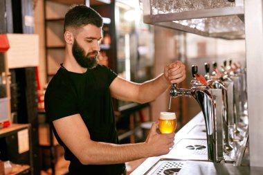 Barmen, Pub Bar çalışma. Fıçı bira bardağında dökme yakışıklı adam. Yüksek çözünürlük.