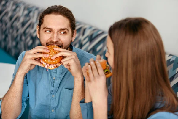 Friends Eating Burgers Indoors. Smiling People Eating Hamburgers In Fast Food Cafe. High Resolution