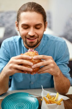 Cafe masada oturan adam Burger Fast Food restoranında yemek. Yüksek çözünürlük.
