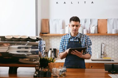 Genç Barista kafe işyeri duran, Tablet üzerinde çalışıyor. Yüksek çözünürlük.