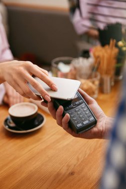 Hareket eden telefon içinde Cafe ile ödeme, eller Closeup ödeme ile kahve dükkanında. Yüksek çözünürlük.