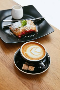 Fincan kahve ve Cafe lezzetli tatlı. Ahşap masa üzerinde ekmek ile taze sıcak içecek. Yüksek çözünürlük.