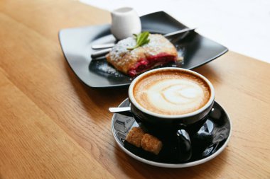 Fincan kahve ve Cafe lezzetli tatlı. Ahşap masa üzerinde ekmek ile taze sıcak içecek. Yüksek çözünürlük.