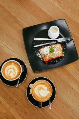 Bir fincan kahve içecek ve tatlı plaka Cafe ahşap tablo üzerinde. Yüksek çözünürlük.