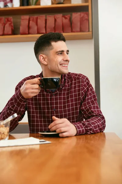 Happy Man Drinking Coffee At Table In Cafe. High Resolution.