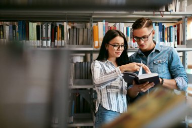 Öğrenciler Üniversite kitaplığında birkaç. Adam ve kadın yakınındaki raflardan kitap okuma. Yüksek çözünürlük