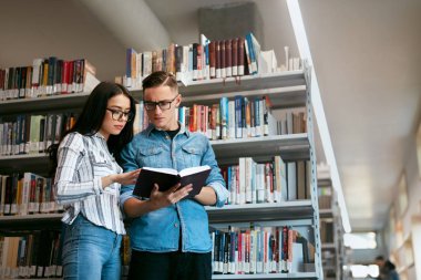 Öğrenciler Üniversite kitaplığında birkaç. Adam ve kadın yakınındaki raflardan kitap okuma. Yüksek çözünürlük
