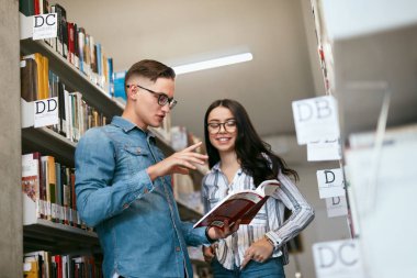 Öğrenciler Üniversite kitaplığında birkaç. Adam ve kadın yakınındaki raflardan kitap okuma. Yüksek çözünürlük