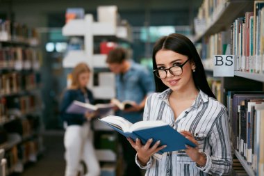 Kitaplığındaki kitap okuma kız. Öğrenci öğrenme, arka plan öğrencilerle ders kitabı okuma. Yüksek çözünürlük