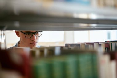 Kitapçı kitapta arayan adam. Öğrenci kitaplığı raflardan ders kitabı bulmaya çalışıyorum. Yüksek çözünürlük