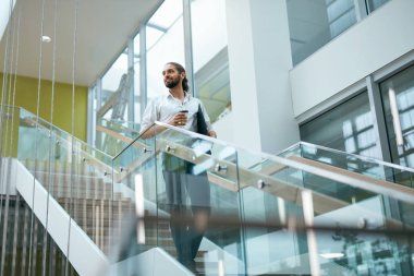 İş adamı ofis binası, eser olacak. Erkek alt klasörle Modern ofis iç merdivenlerden yukarı gidiyor. Yüksek çözünürlük