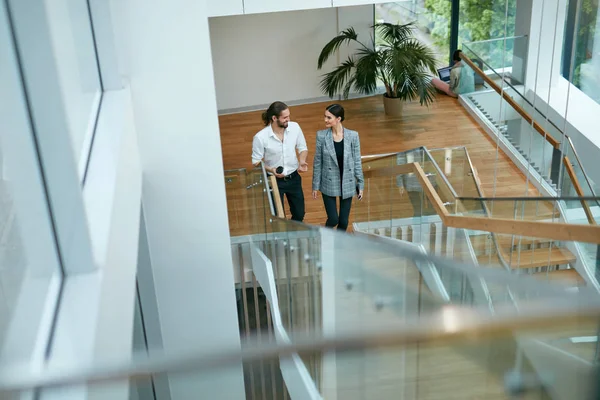 Business People In Office Going To Work. Beautiful Man And Woman Going Up Stairs In Modern Business Center. High Resolution