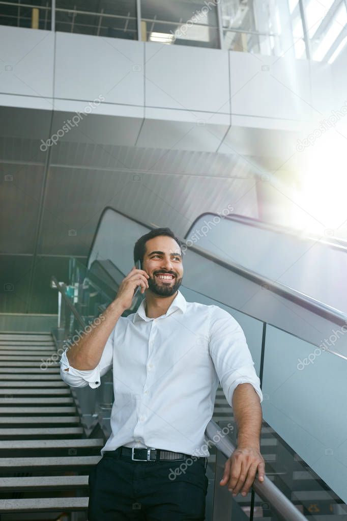 Business Man Talking On Mobile Phone In Office On Stairs. Portrait Of Male Worker Working Using Phone. High Resolution