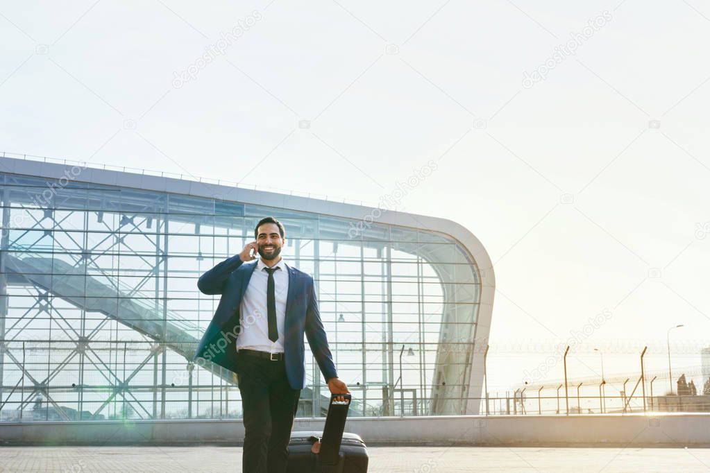 Business Man Talking On Mobile Phone Outdoors. Man With Suitcase Traveling On Business Trip. High Resolution