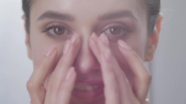 顔のケア。魅力的な女性の目のクローズ アップの下の皮膚に触れる — ストック動画