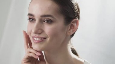 Cilt Bakımı. Yüz parmaklarıyla dokunarak gülümseyen güzel kadın 