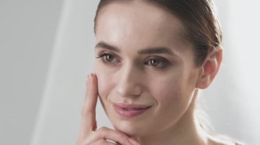 Cilt Bakımı. Yüz parmaklarıyla dokunarak gülümseyen güzel kadın 