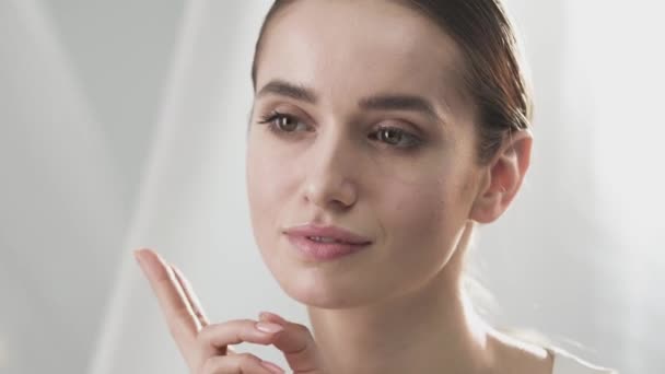 Bőrápolás. Szép mosolygó nő megérintette ujjával arcát — Stock videók